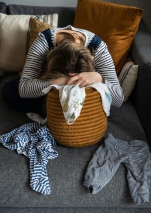 Woman face down in pile of laundry - Image by Monika Grabkowska